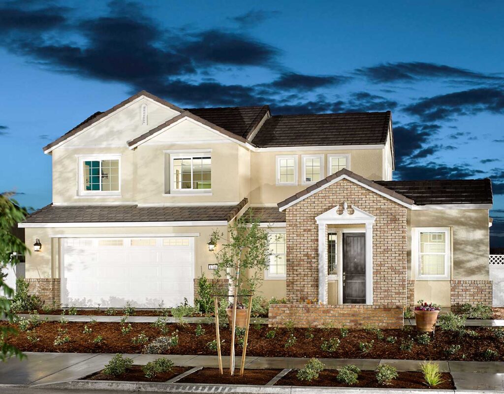 A two-story suburban home at dusk, featuring a double garage, stone and stucco facade, with a neatly landscaped front yard and a clear blue sky.